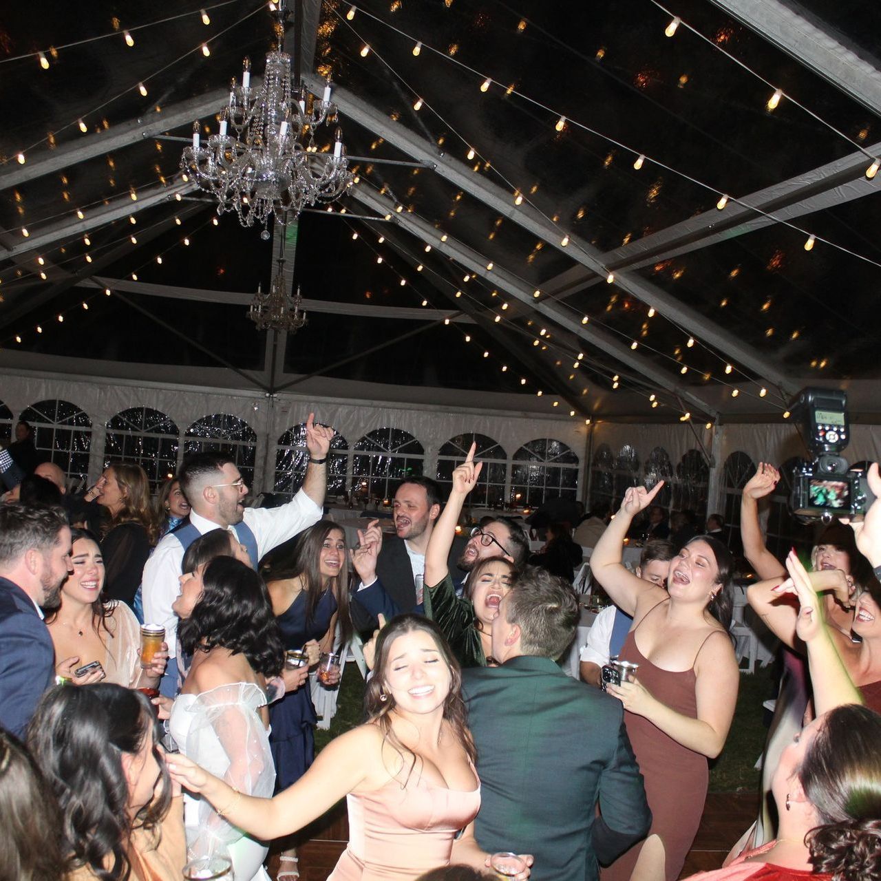 A group of people are dancing under a clear tent