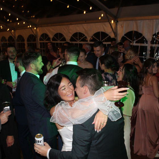 A man holding a can of miller lite is hugging a woman