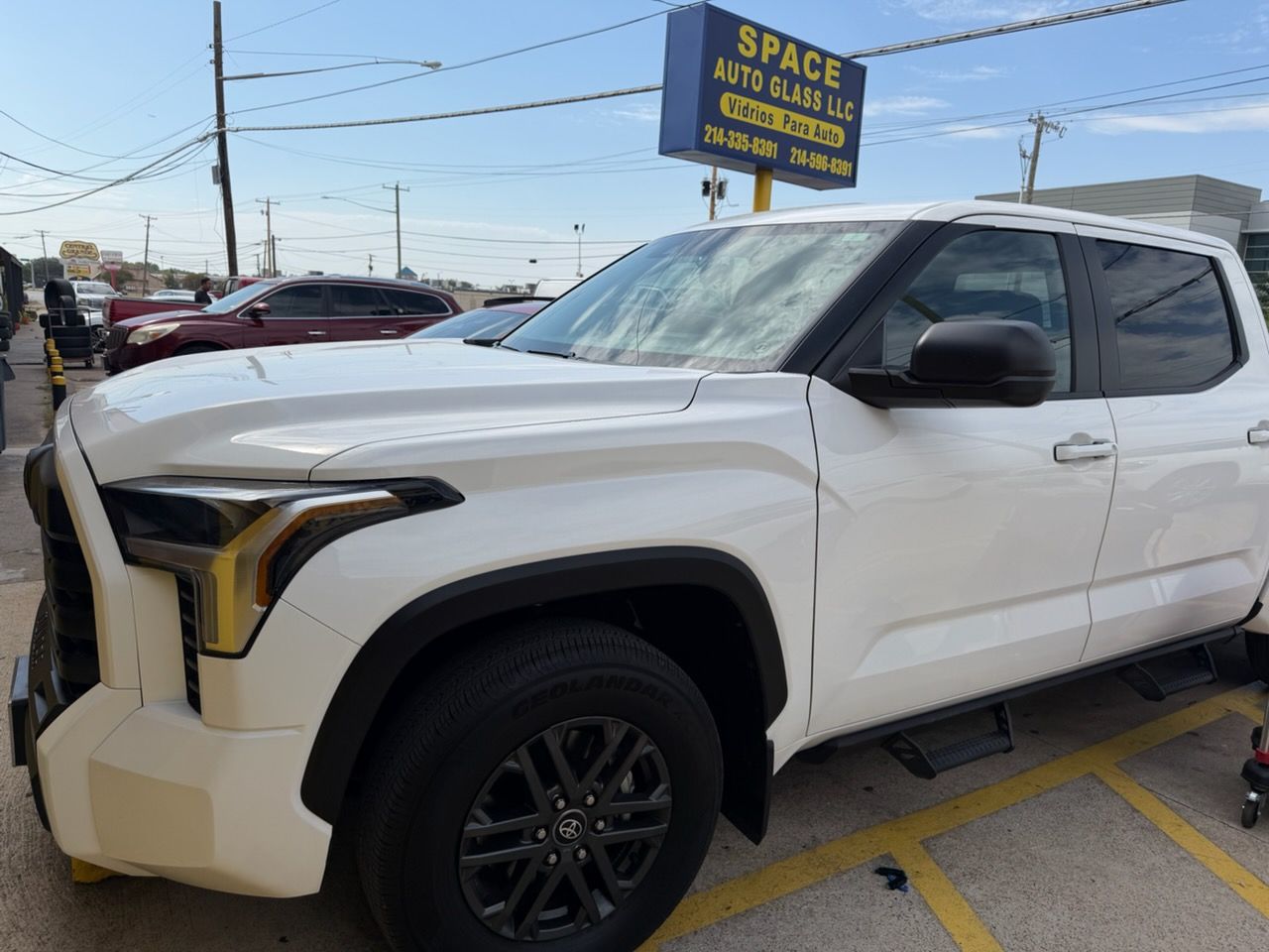 White pickup truck parked in a lot, viewed from the front passenger side under a cloudy sky