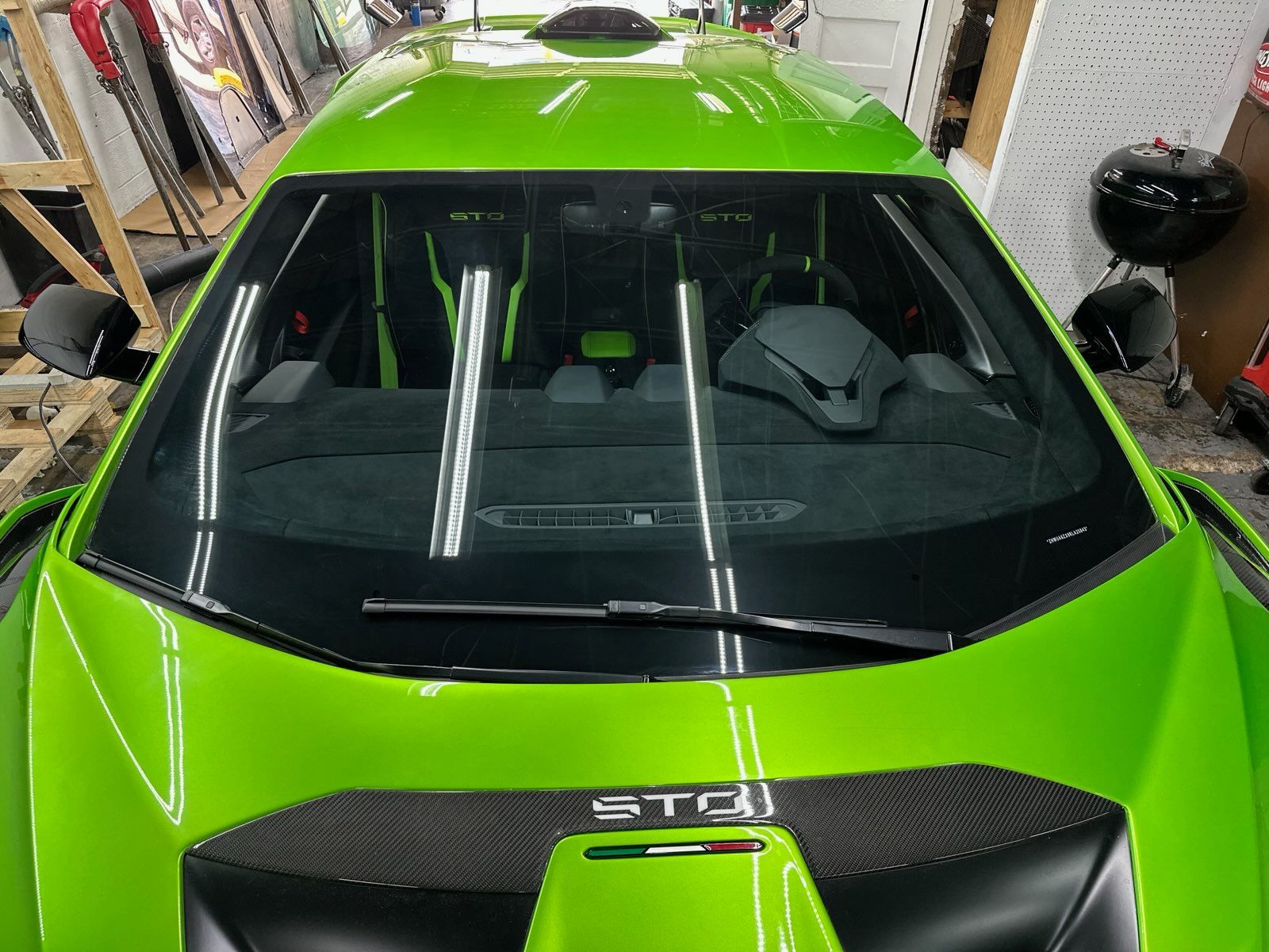 Bright green sports car with black roof and windshield, viewed from above in a garage