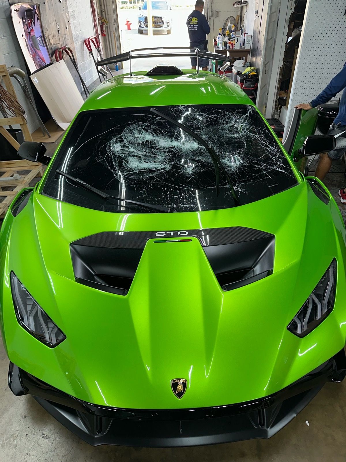 Bright green Lamborghini with shattered windshield in a garage