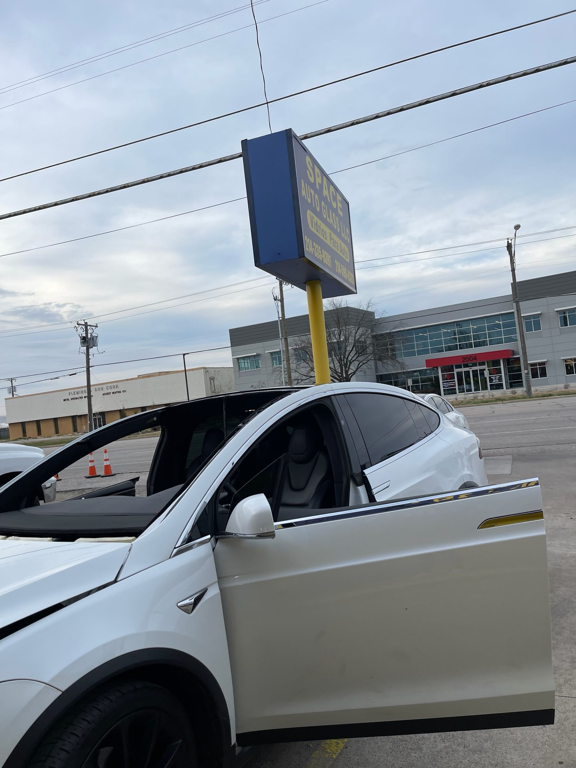 White car with open door at a roadside parking area under a cloudy sky