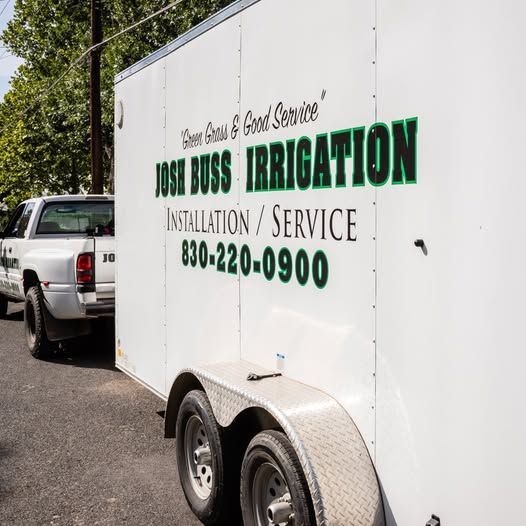 White irrigation service trailer with green “Josh Buss Irrigation” lettering parked beside a pickup truck.