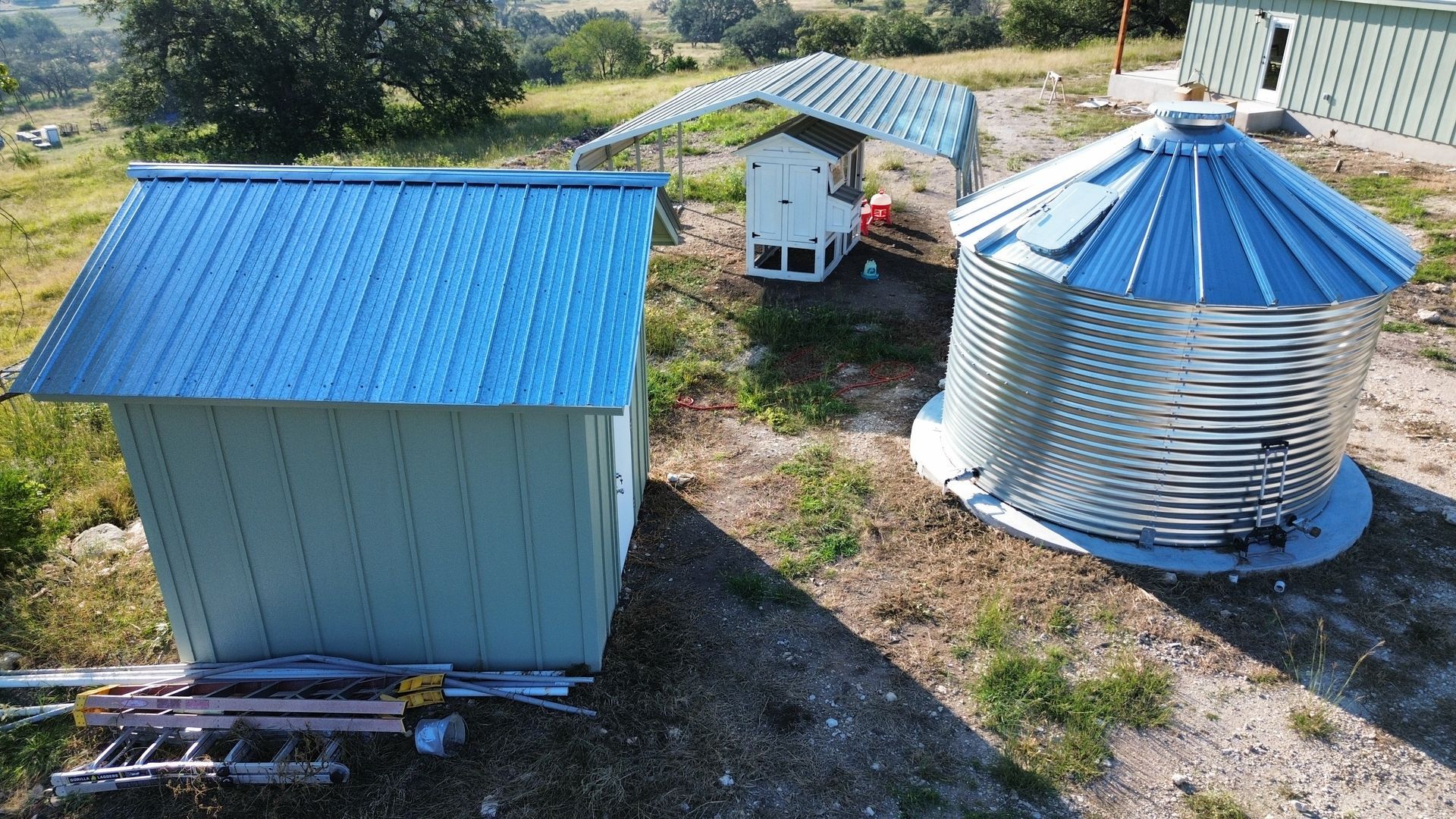 Blue-roofed farm buildings and a grain silo in a rural field