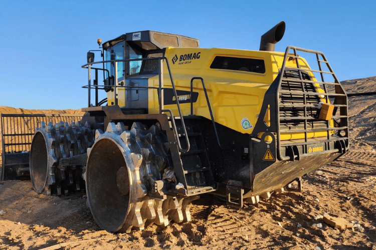 Yellow BOMAG mining vehicle on dirt road in an open pit mine, with SCAN~LINK's antenna attached.