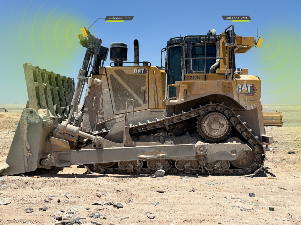 Yellow bulldozer pushing dirt in a dusty mining site with two SCAN~LINK antennas