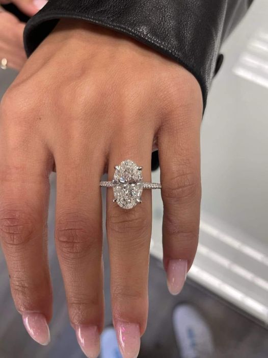 Hand with long pink nails wearing a large diamond ring and black leather sleeve