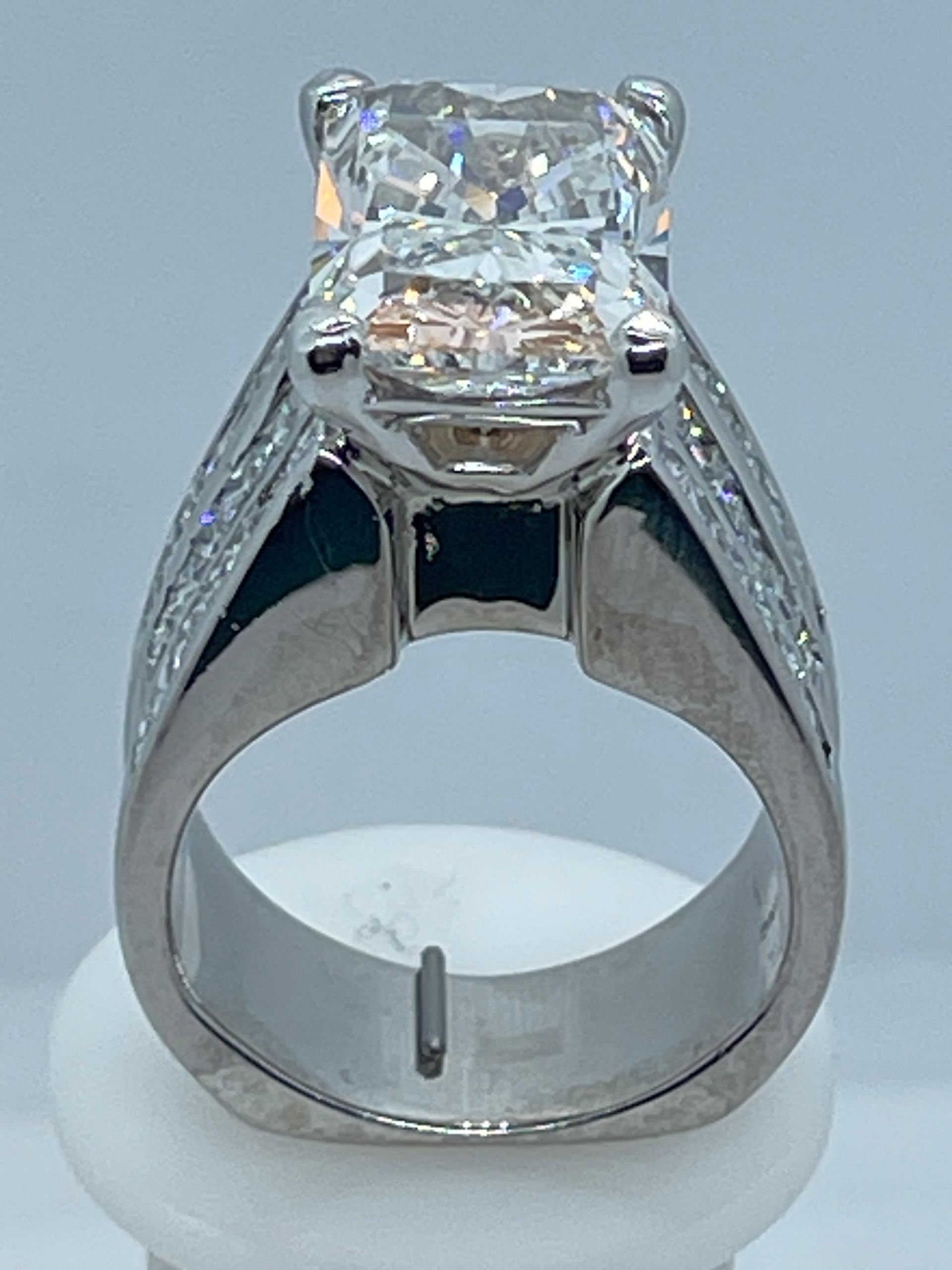 Silver diamond ring with a large square-cut center stone on a display stand