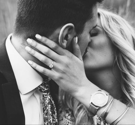 Couple kissing in black-and-white, her hand on his face and an engagement ring visible
