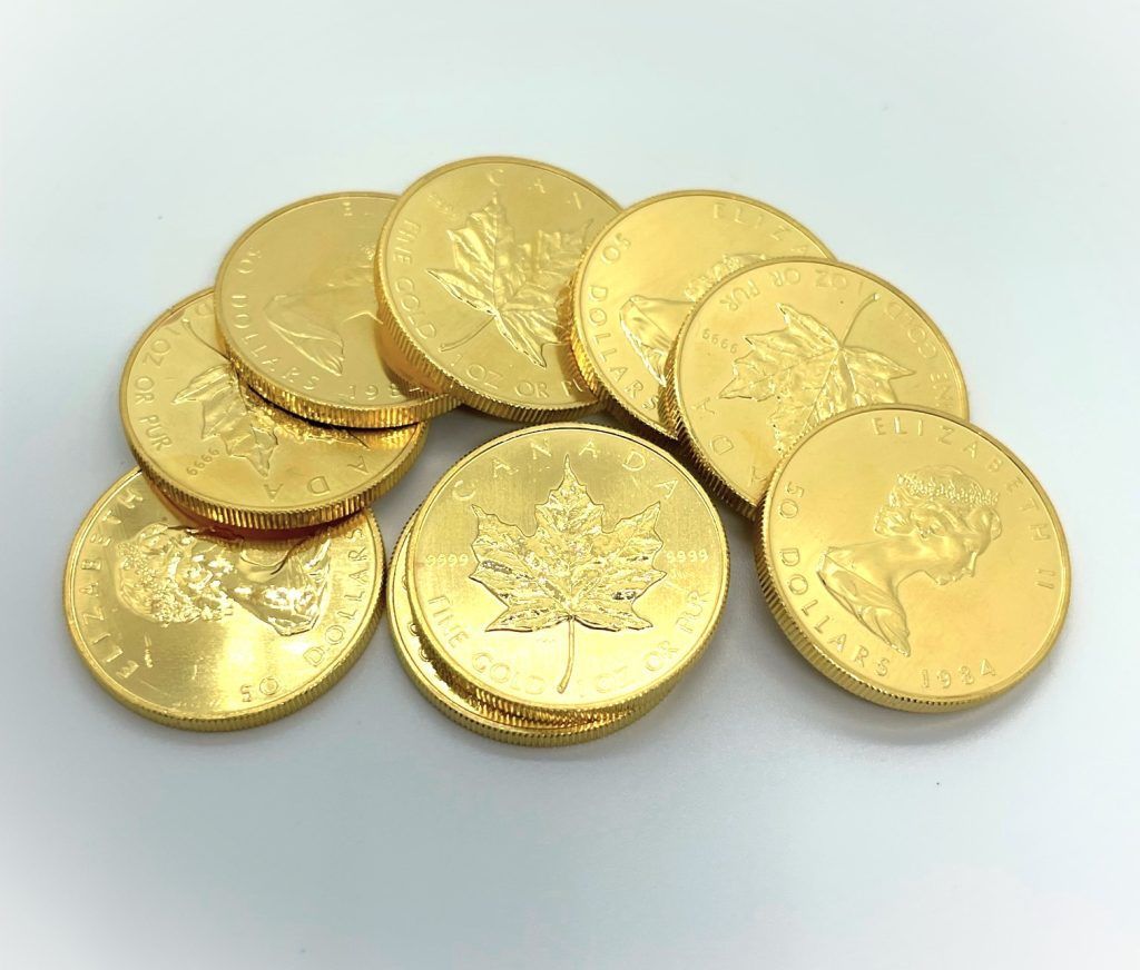 Several gold coins stacked and scattered on a white surface.