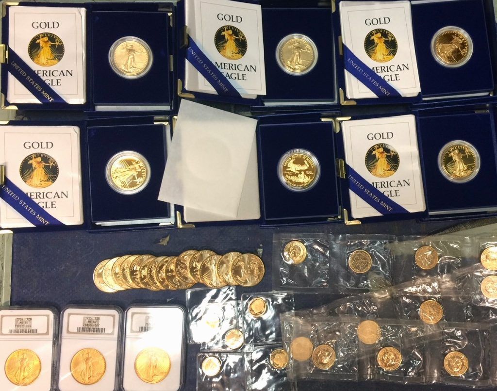 Display of gold coins and medallions in blue cases and clear packaging on a table.