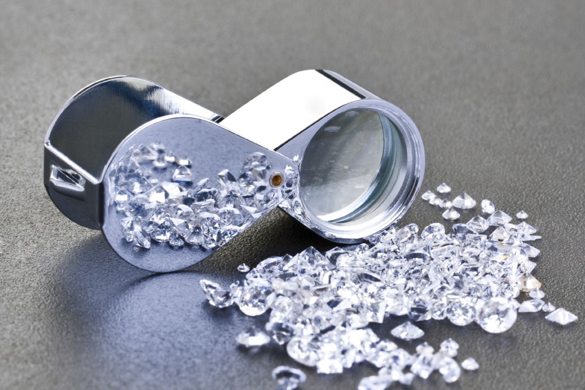 Spilled silver capsules from a tipped metal bottle on a gray surface