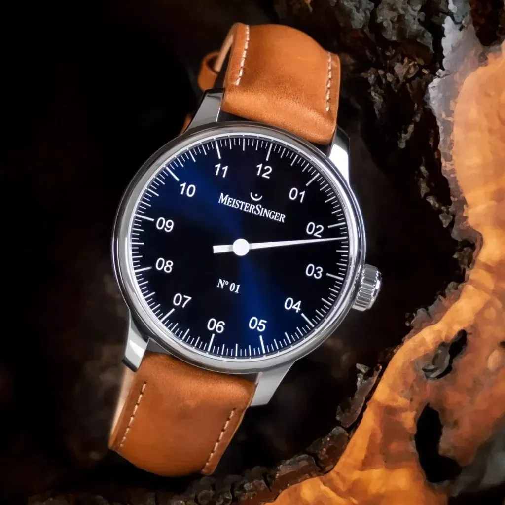 Brown leather-strap wristwatch with black dial and white numerals on a wooden surface