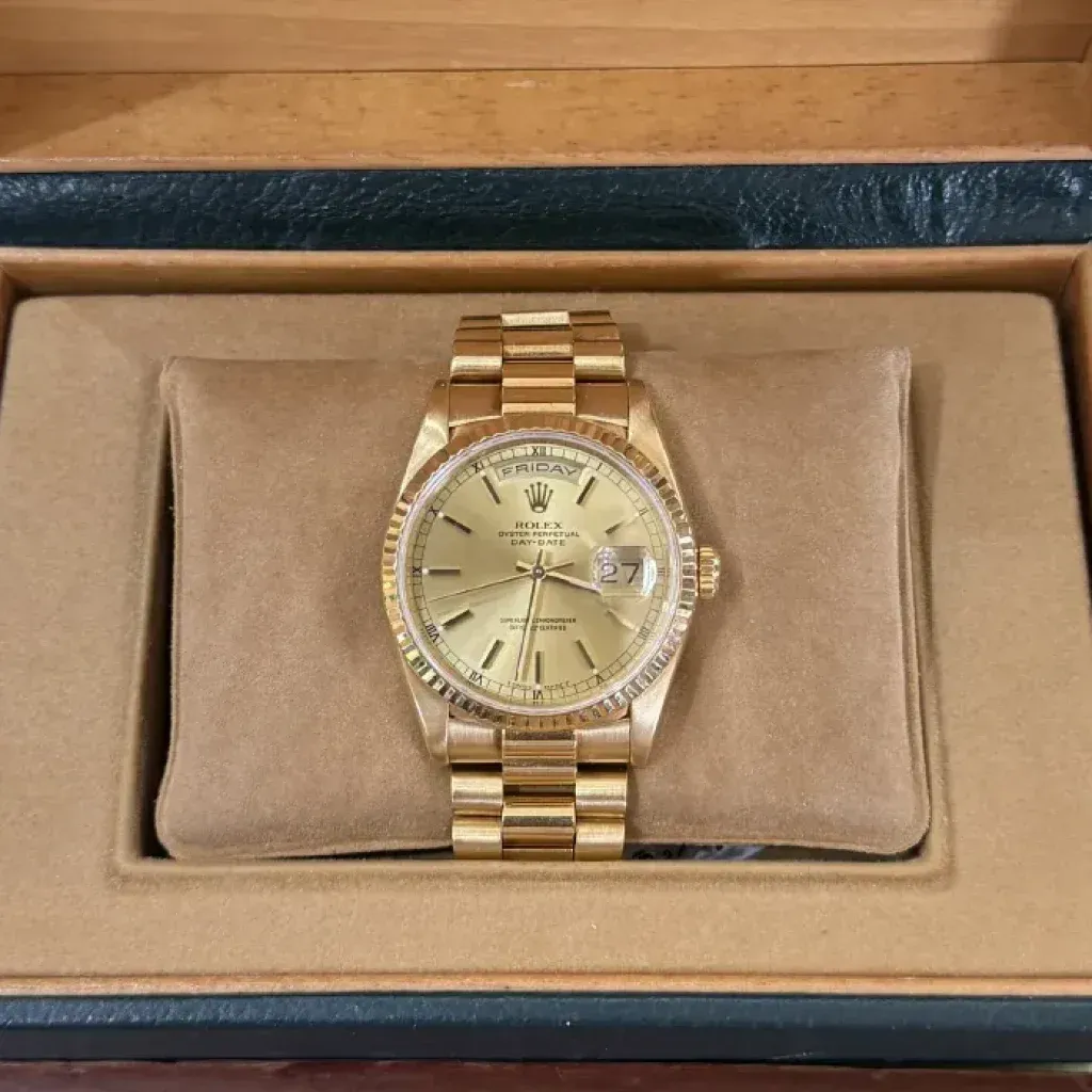 Gold wristwatch in a presentation box on a beige cushion