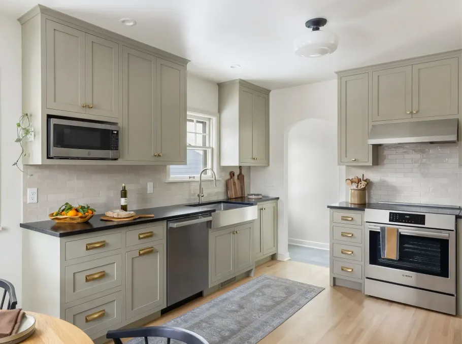 Bright modern kitchen with gray cabinets, stainless appliances, and a small rug on the light wood floor