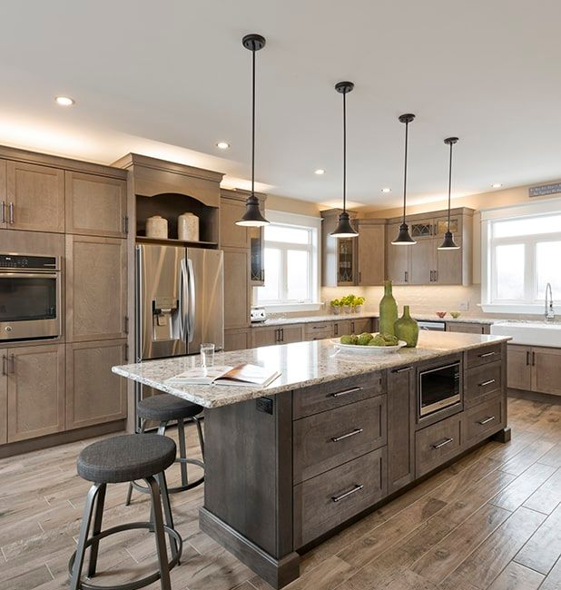Modern kitchen with gray wood cabinets, marble island, pendant lights, and stainless steel appliances
