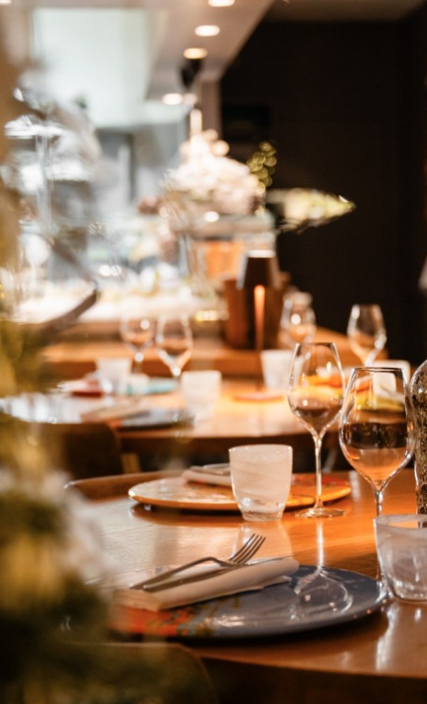 Elegante tavolo da pranzo apparecchiato con piatti, bicchieri da vino e calda illuminazione a lume di candela in un ristorante.