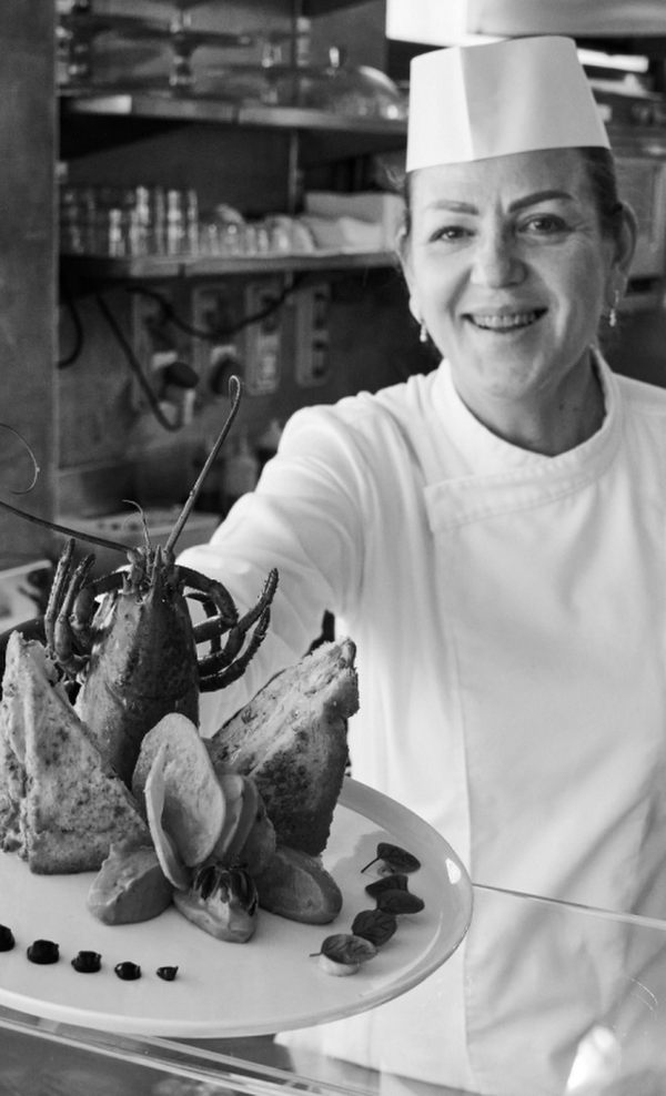 Lo chef presenta un piatto di pesce impiattato nella cucina di un ristorante.