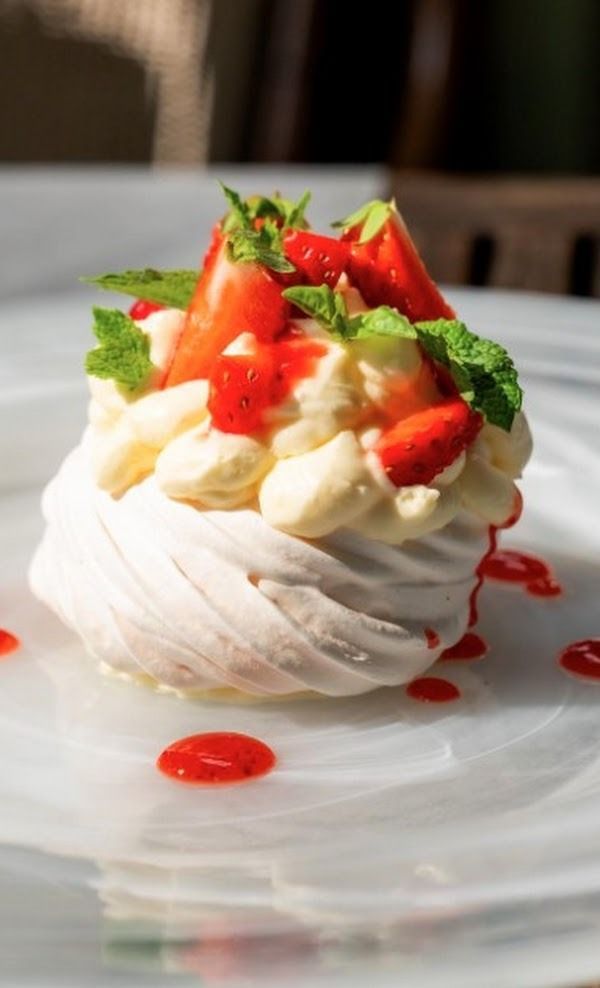Dessert cremoso con fragole, servito su un piatto bianco e guarnito con salsa rossa.
