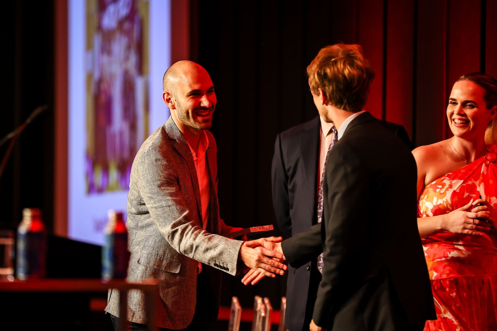 A group of people are shaking hands on a stage.