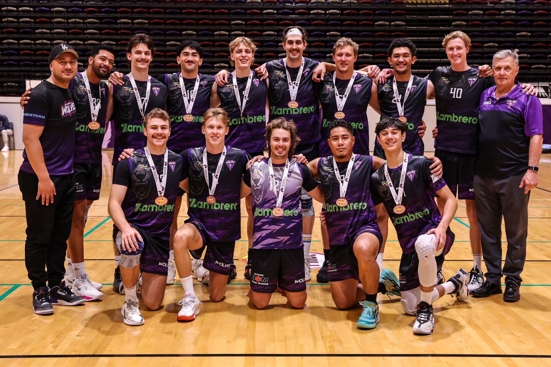 A group of young men are posing for a picture on a basketball court.