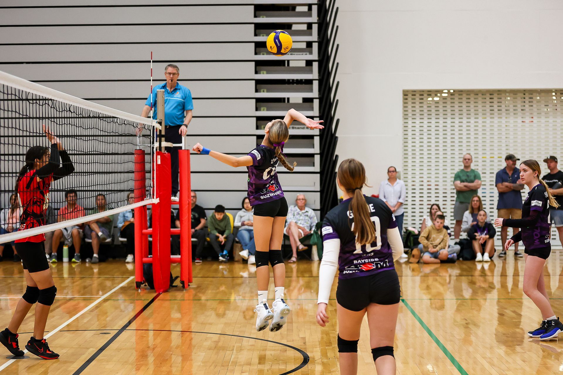 A group of girls are playing volleyball in a gym.