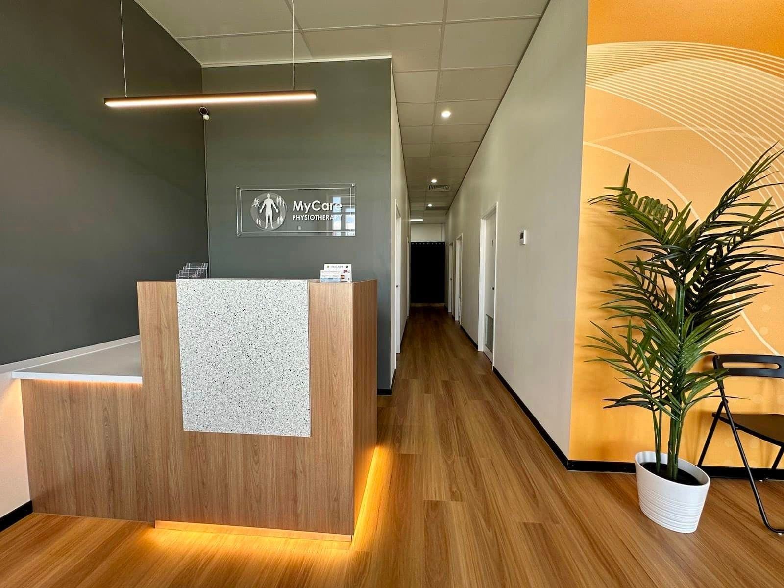 A reception desk in a hallway with a plant in a pot.