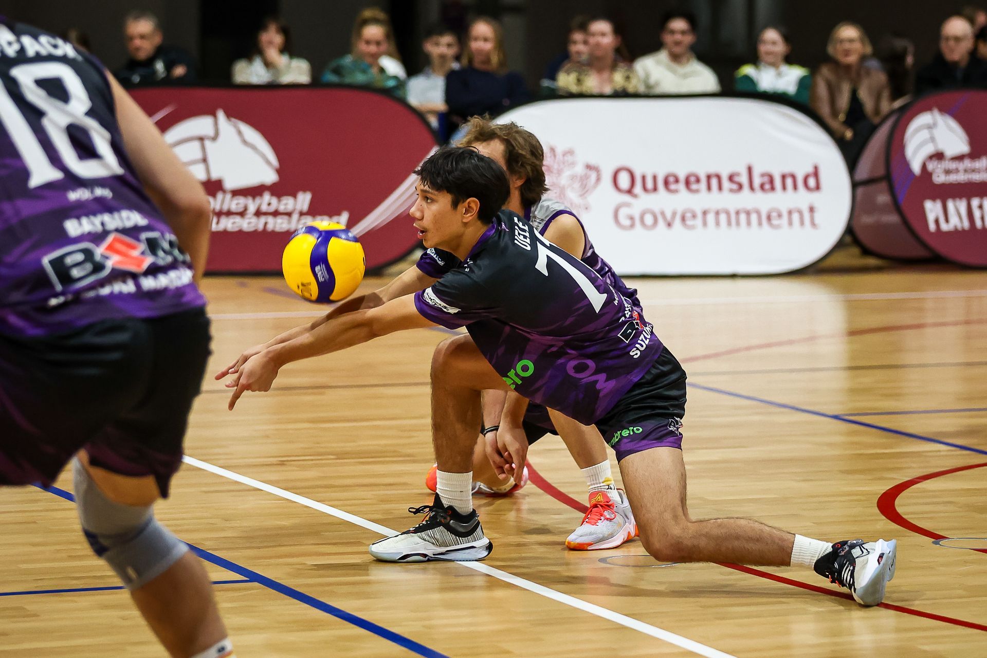 A group of people are playing volleyball on a court.