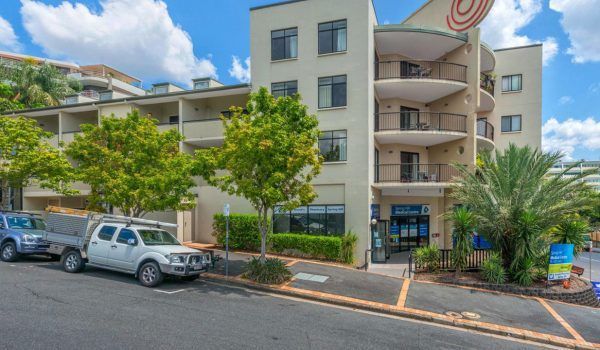 A large apartment building with cars parked in front of it.