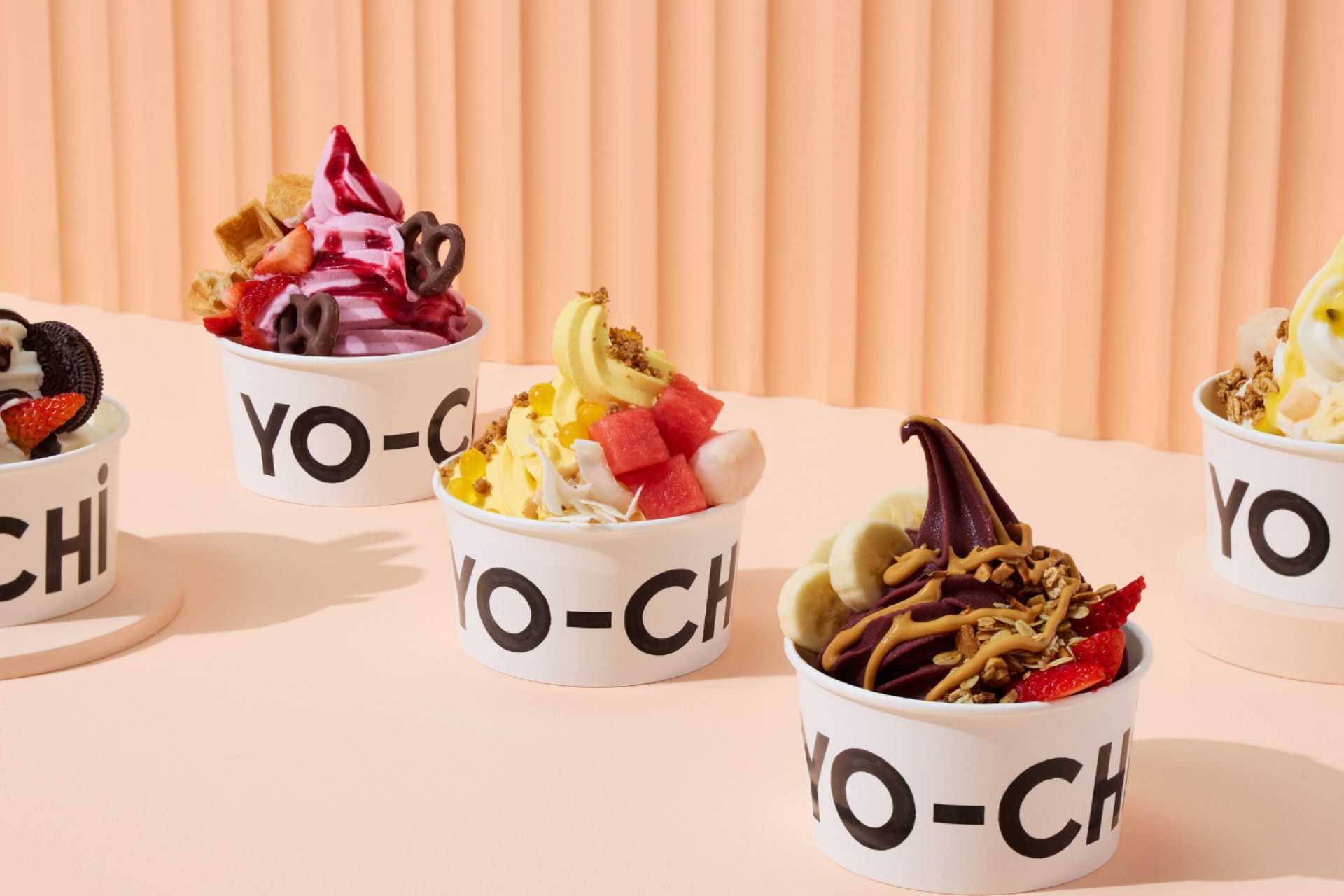 Four cups of ice cream with different toppings are sitting on a table.