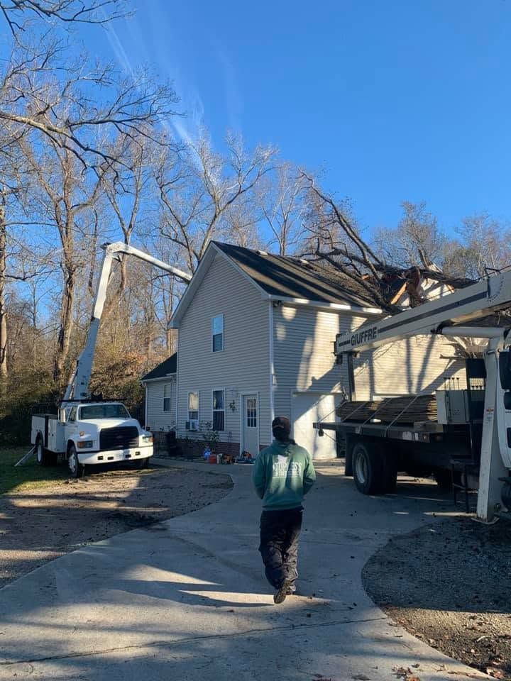 Person walking toward a house with storm damage and a bucket truck in the driveway