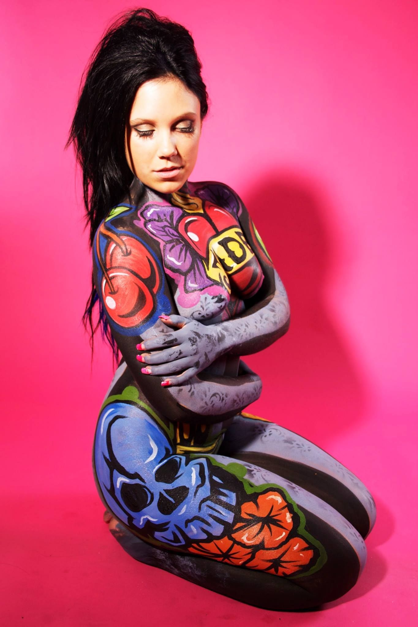 A woman is kneeling down with her body painted.