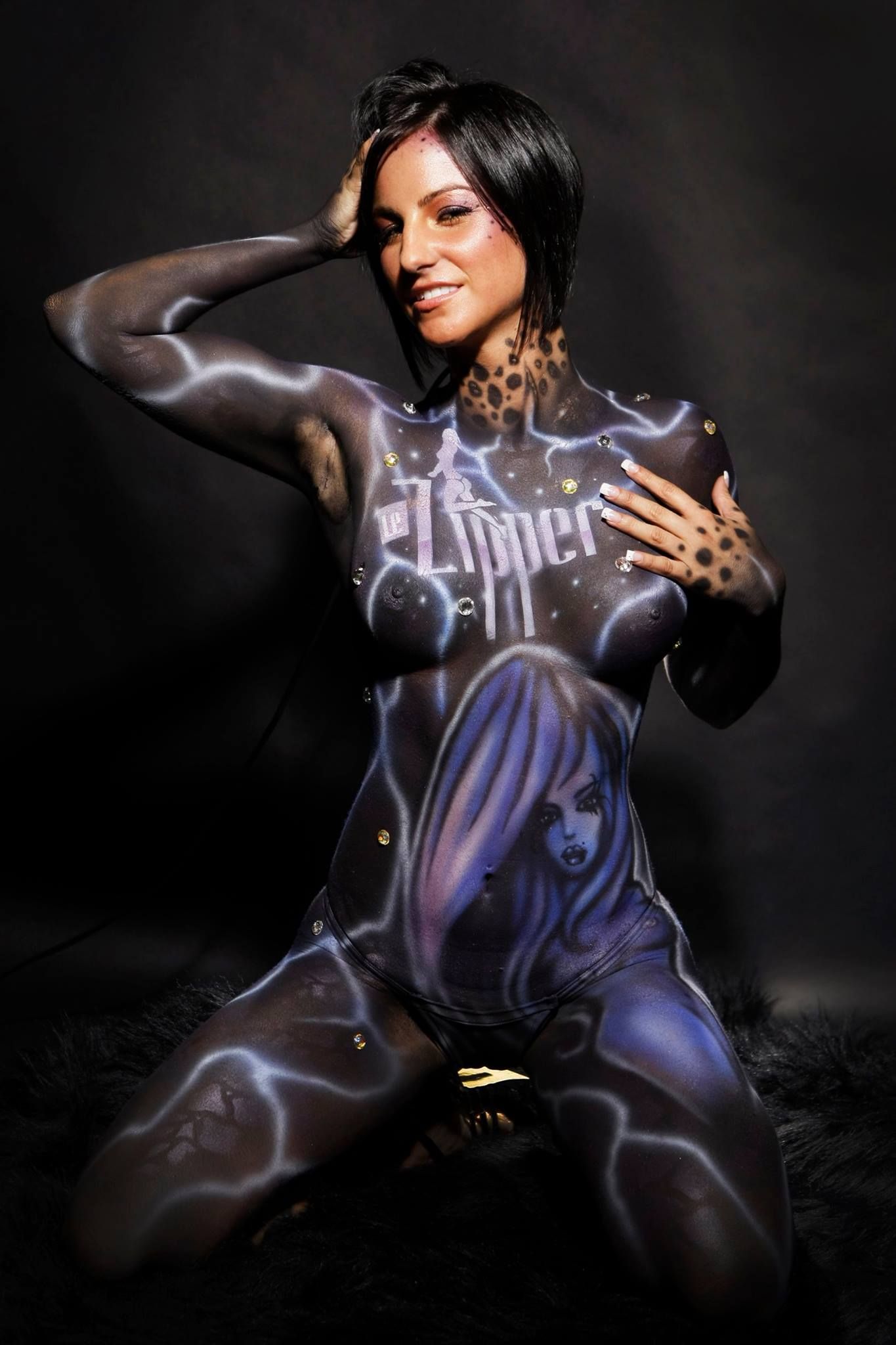 A woman is kneeling down with her body painted.