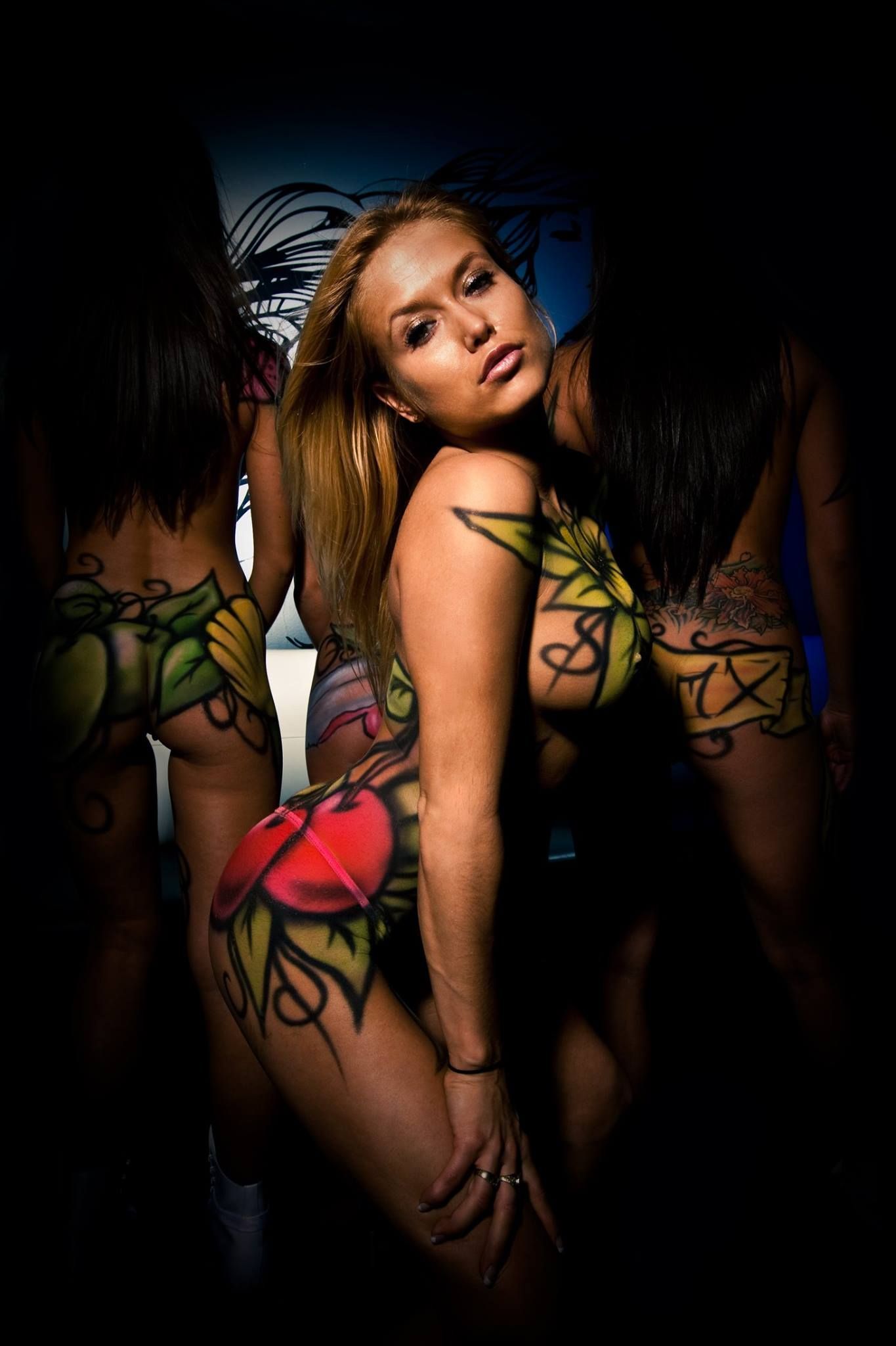 Three women are standing next to each other with their bodies painted.