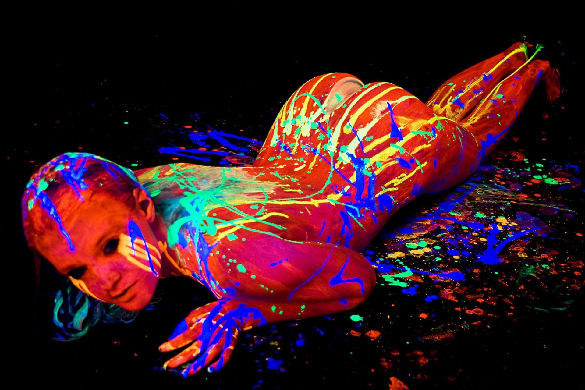 A woman is covered in glow in the dark paint.