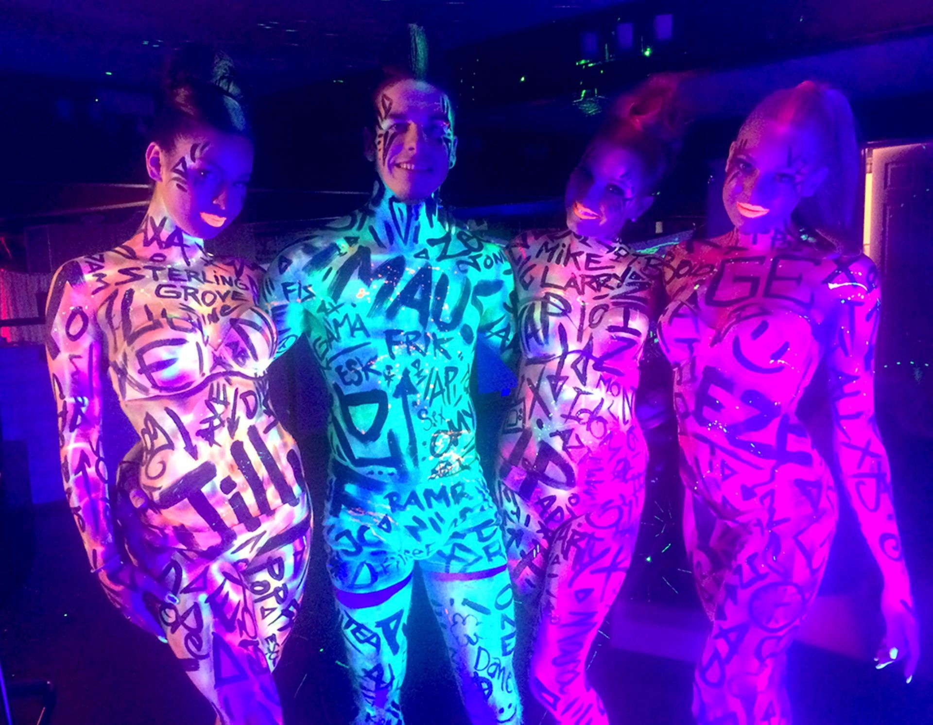A group of people are standing next to each other with their bodies painted with graffiti.
