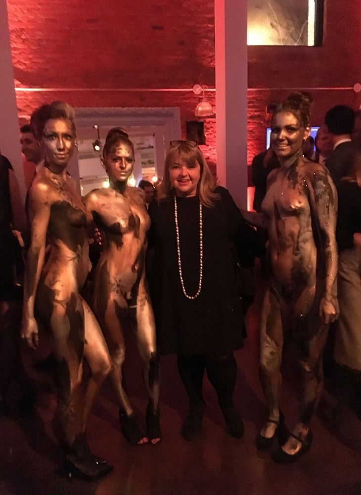 A woman is standing next to a group of women painted gold