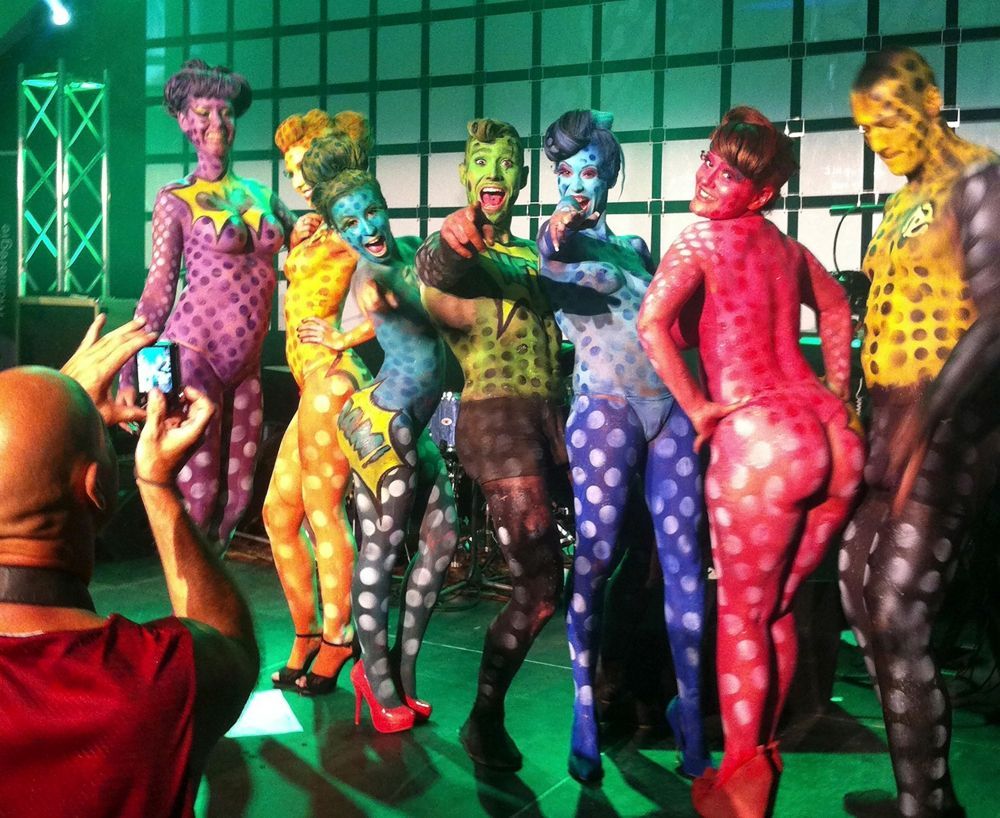 A man is taking a picture of a group of people painted in different colors