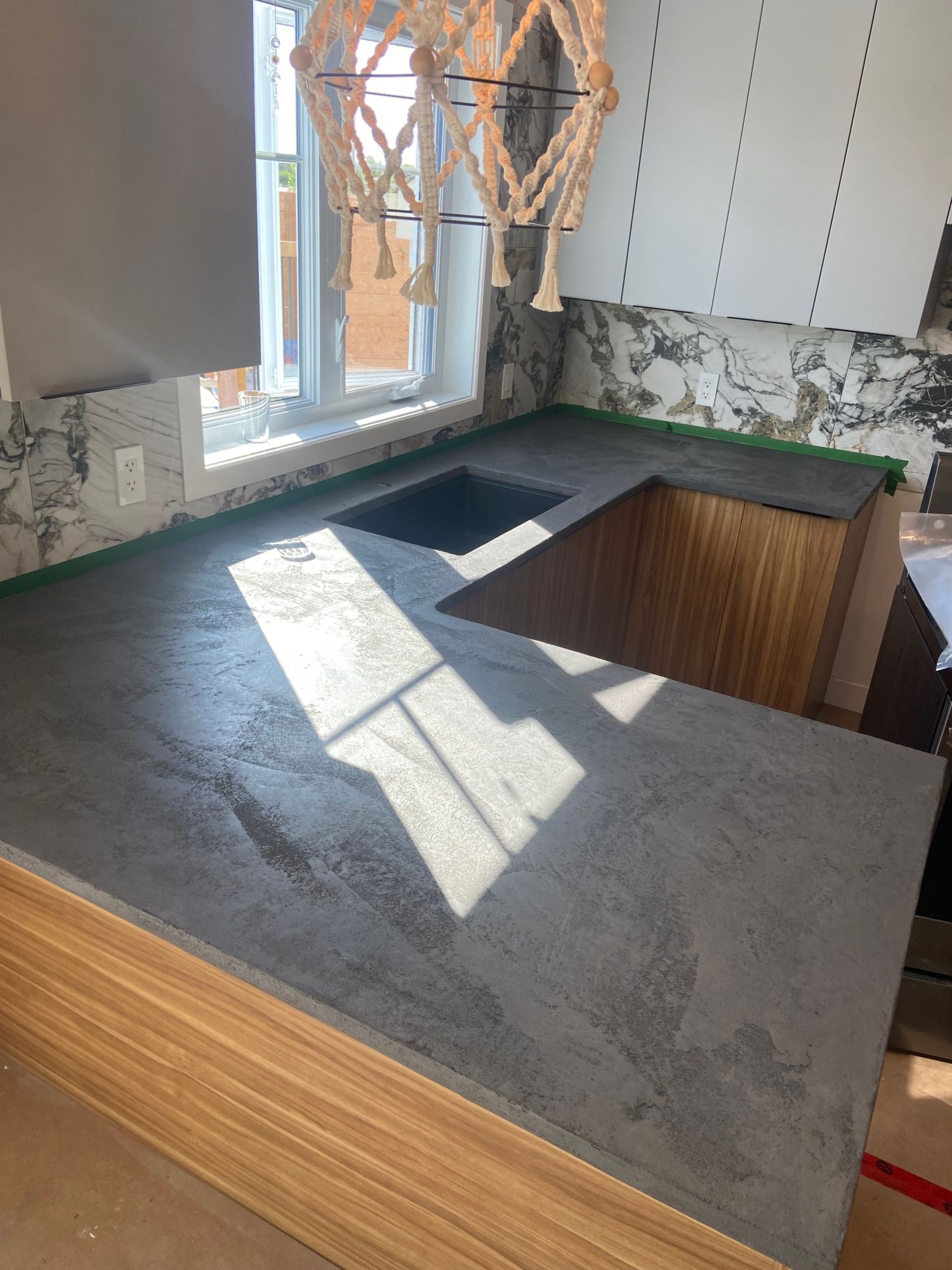 A kitchen with a concrete counter top and a sink.