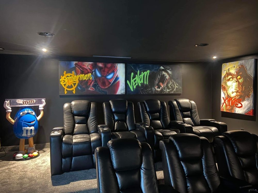 A home theater with black leather seats and a m & m statue.