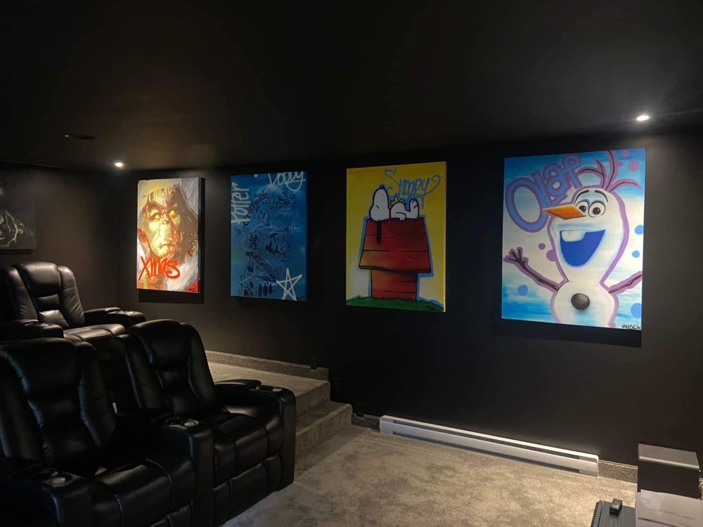 A home theater with snoopy and olaf paintings on the wall.