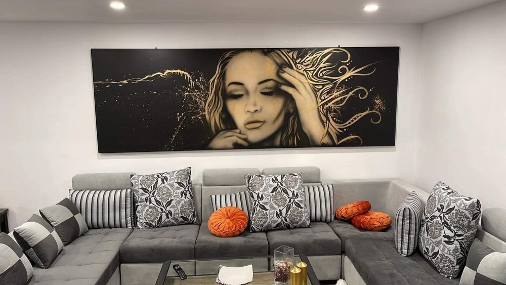 A living room with a couch and a painting of a woman on the wall.