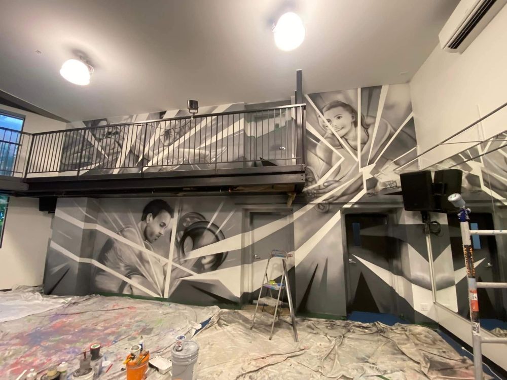 A large mural is being painted on the wall of a room.