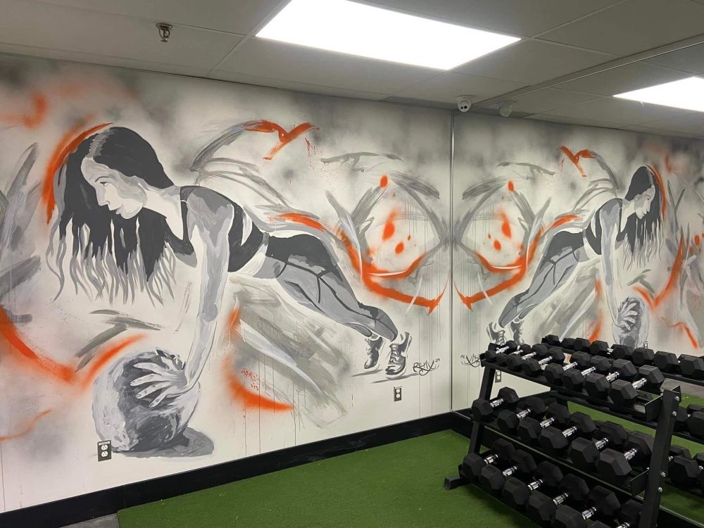 A gym with a mural on the wall of a woman holding a ball.