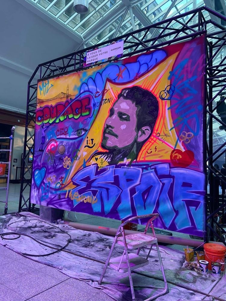 A large graffiti painting of a man is being painted on a wall.