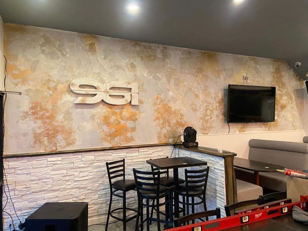 A restaurant with tables and chairs and a tv on the wall.
