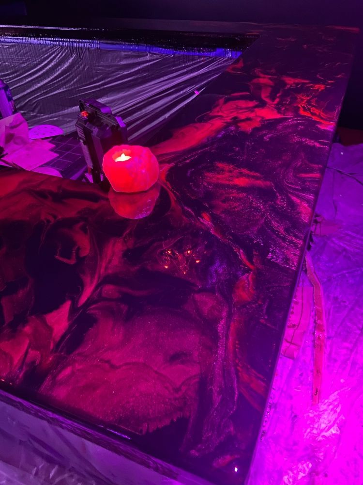 A candle is sitting on top of a table under a purple light.