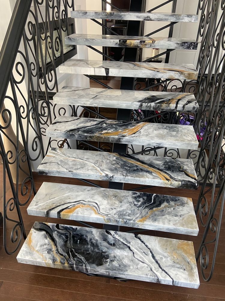 A staircase with marble steps and a wrought iron railing.