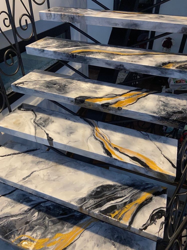 A close up of a staircase with marble steps and a wrought iron railing.