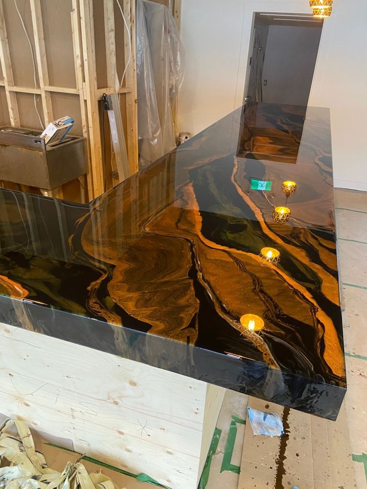A black and gold counter top is sitting on a wooden floor in a room.